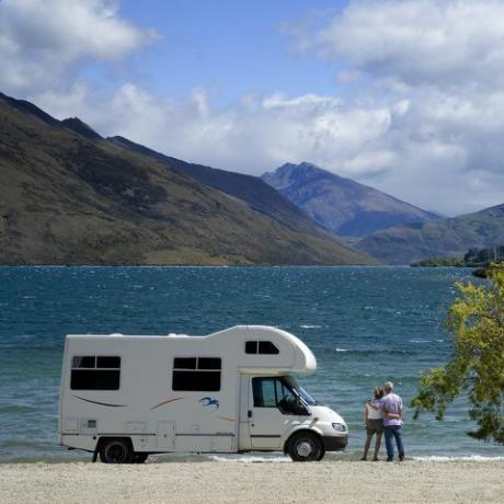 casal fora do trailer olhando para o lago