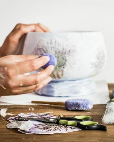 oficina de artista de decoupage tesoura, esponja, pincel, lápis e mãos pintadas de um hobby decorando um vaso com padrão de lavanda