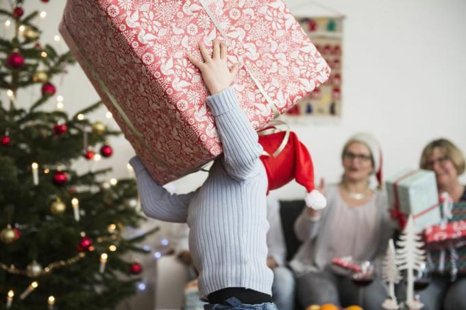 Garotinho carregando uma grande caixa de papelão durante o Natal