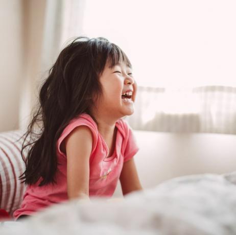 Menina rindo alegremente na cama