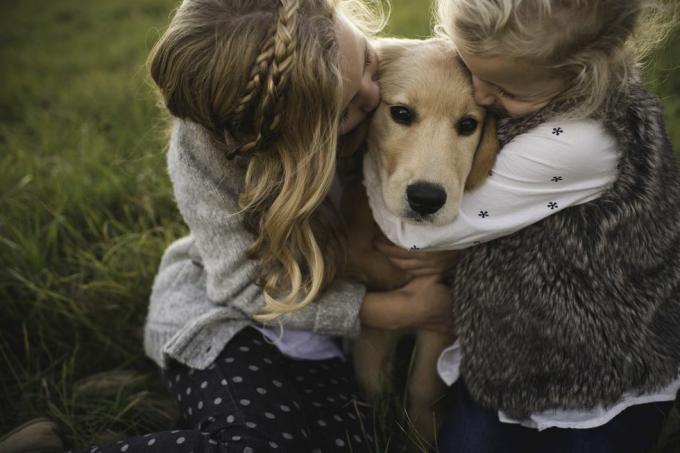 duas meninas abraçando cachorro de estimação, ao ar livre