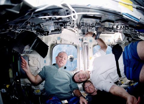 Uma visão de baixo ângulo no convés de popa do Space Shuttle Discovery registra três tripulantes e uma cena da janela da Estação Espacial Internacional (ISS) que se aproxima. Na foto estão os astronautas Brian Duffy (à esquerda), comandante; Pamela Melroy, piloto; e Peter J.K. (Jeff) Wisoff, especialista em missões.