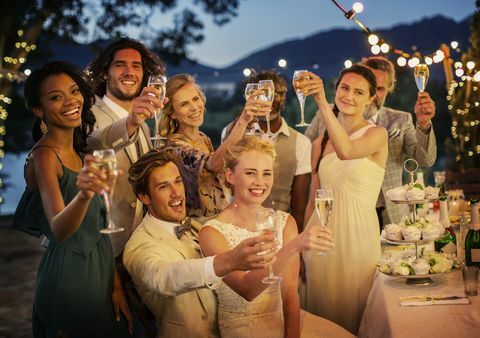 Convidados do casamento brindando com champanhe durante a recepção de casamento no jardim