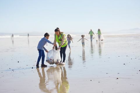 Mãe e filho voluntários limpeza lixo na ensolarada praia de areia molhada