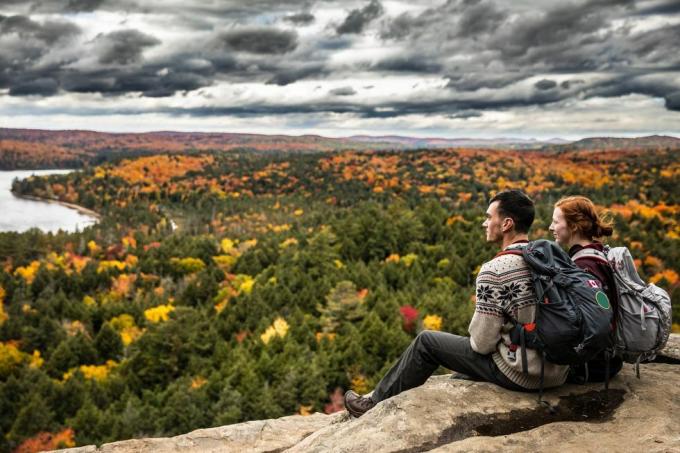 jovem casal relaxando olhando a vista do lago e a folhagem de outono nas montanhas