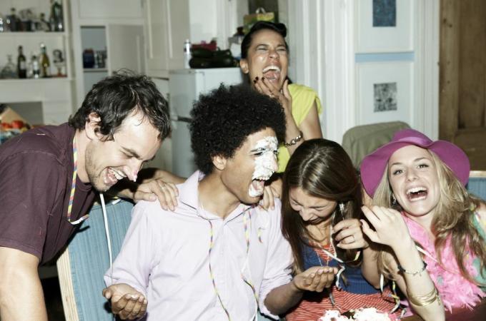 homem com glacê no rosto rindo com amigos