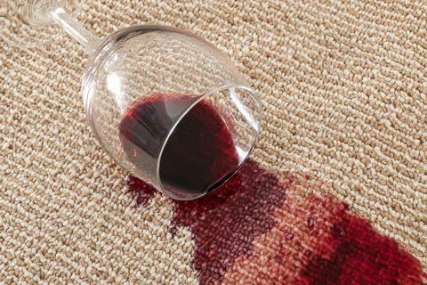 acidente doméstico e conceito de acidente doméstico com close-up de um copo derramado de vinho tinto no tapete marrom