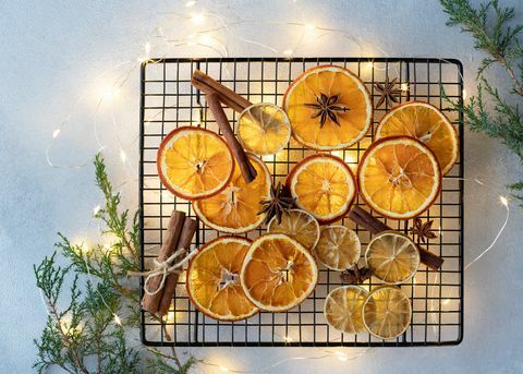 laranjas secas, limões, paus de canela e estrelas de anis em um fundo de luzes de natal e ingredientes de ramos de abeto para cozinhar ou decoração de natal espaço plano para texto