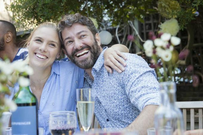 casal rindo almoçando com amigos no pátio do jardim