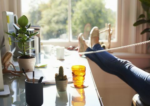Mulher falando no telefone no escritório em casa - apenas pés e pernas mostrados
