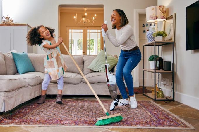 Foto de mãe e filha se divertindo enquanto limpam a sala