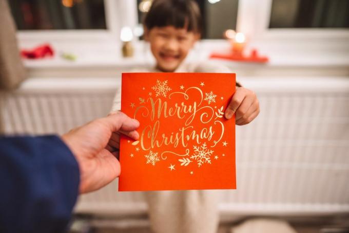 perspectiva pessoal de um pai recebendo um cartão de natal dado por sua adorável filha alegre no natal em casa conceito de celebração de natal com a família em casa