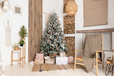 decorado interior da sala de estar de natal com belas caixas de presente de abeto no chão, lenha para uma lareira