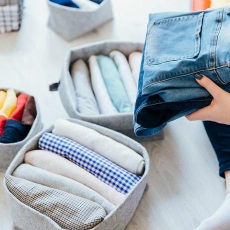 mulher dobrando roupas no quarto, organizando roupas em caixas e cestos conceito de estilo de vida minimalista e sistema de dobragem de camisetas japonesas método konmari