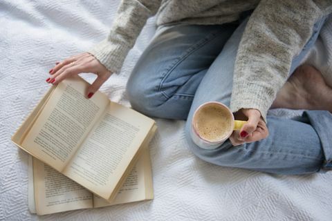 Mulher na cama com café e livro