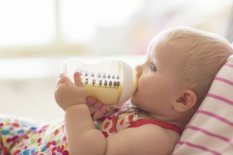 Menina, bebendo da garrafa no sofá