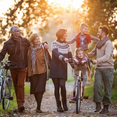 família sorridente de várias gerações passeando de bicicleta na natureza e aproveitando o tempo juntos