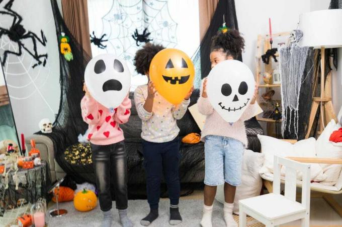 crianças caucasianas brancas e afro-americanas felizes recebendo festa de halloween em sua casa