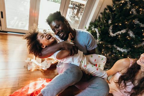 jovem pai australiano acaricia e ri com a filha após abrir os presentes na manhã de natal