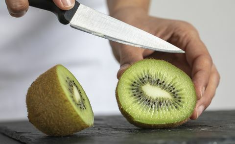 uma mulher cortando kiwi