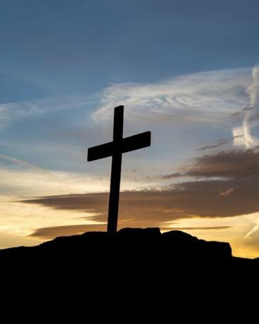 cruz de madeira no topo de uma colina ao pôr do sol