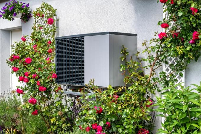 unidade externa de um sistema de aquecimento com bomba de calor rodeada de flores