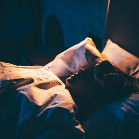mulher com insônia jovem deitada na cama com a mão na testa