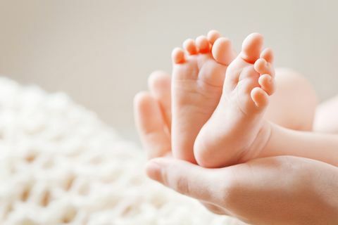 Pés de bebê nas mãos da mãe. Mãe e filha.