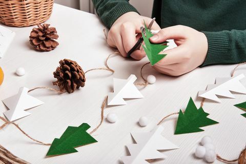 DIY decoração de natal de materiais naturais mãos fazem guirlanda de árvores de papel, barbante e cones