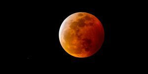 uma lua de sangue ou lua cheia com uma sombra avermelhada devido a um eclipse lunar total, no céu noturno