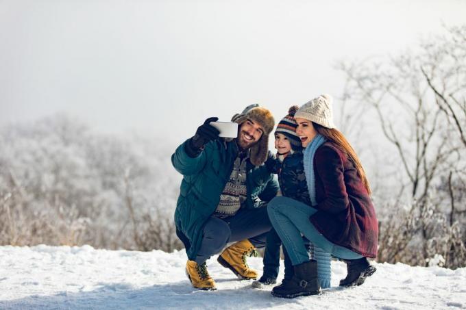 família tirando selfie em dia de inverno na floresta nevada