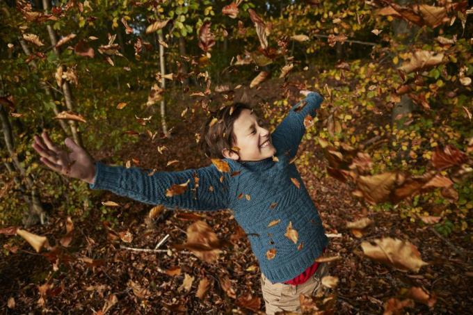 menino alegre desfrutando em meio à queda das folhas de outono