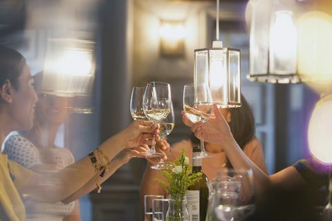 Amigos de mulheres brindando com taças de vinho branco, jantar na mesa do restaurante