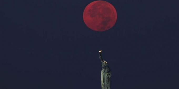 lua cheia se põe atrás da estátua da liberdade em Nova York