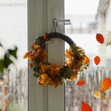 guirlanda de outono DIY de folhas coloridas vermelhas, marrons e amarelas na janela no dia chuvoso de outono