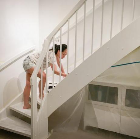 mulher aplicando tinta branca fresca nas escadas