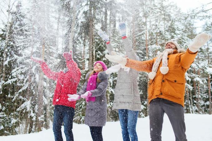 grupo de homens e mulheres sorridentes na floresta de inverno